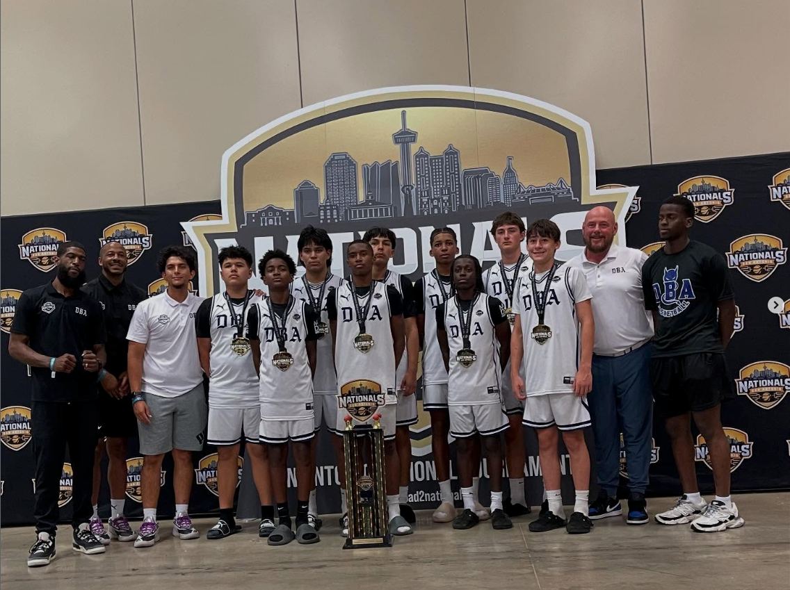 DBA Blue Devils team at Nationals — coaches, players in DBA uniforms with medals and championship trophy